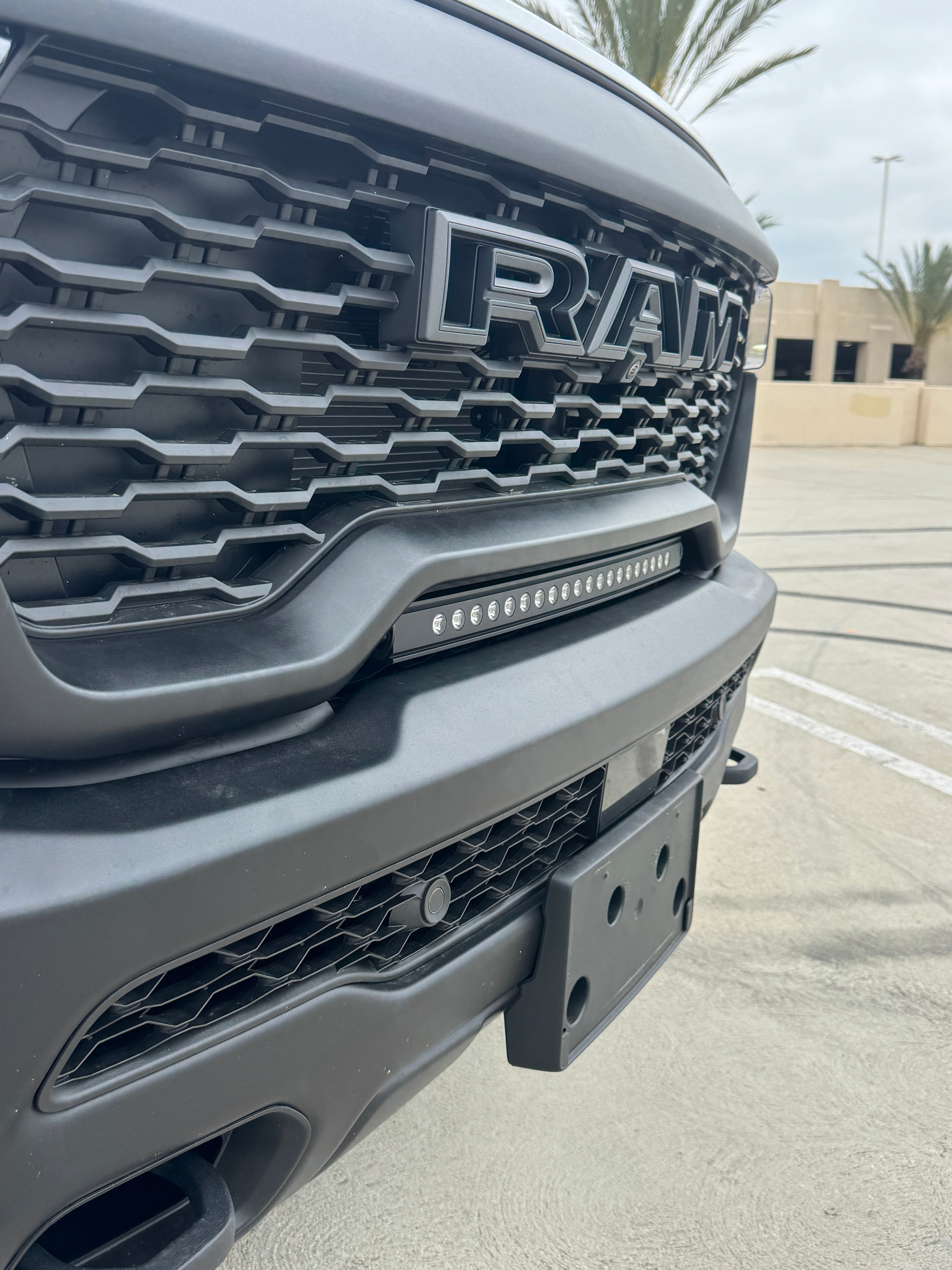 RAM RHO lightbar on 2025 RAM 1500 Rebel, slim curved light bar installed between grille and bumper with black powder-coated bracket