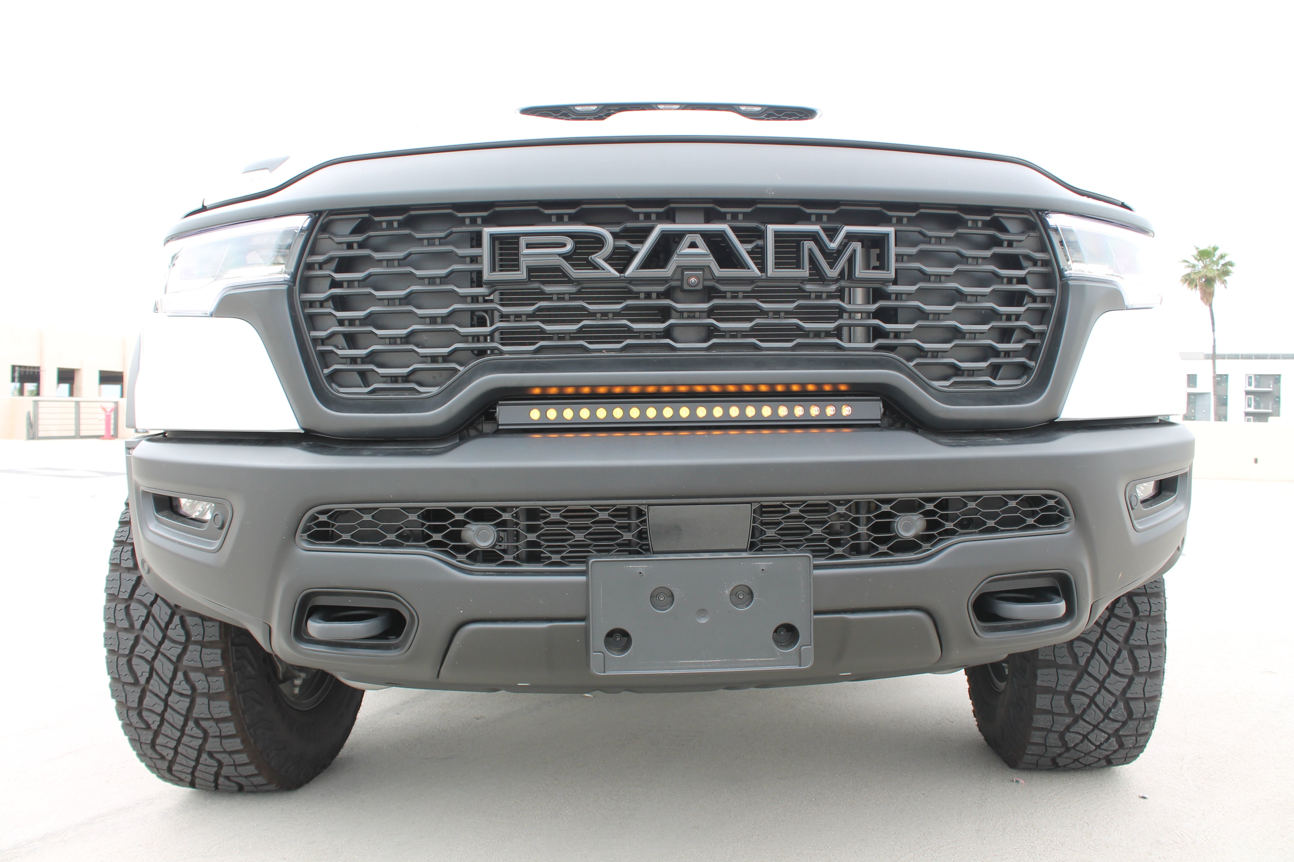 RAM RHO lightbar 2025+ 23in Slim installed on RAM 1500 Rebel; curved slim light bar between grille and bumper, black powder-coated bracket, two installation options