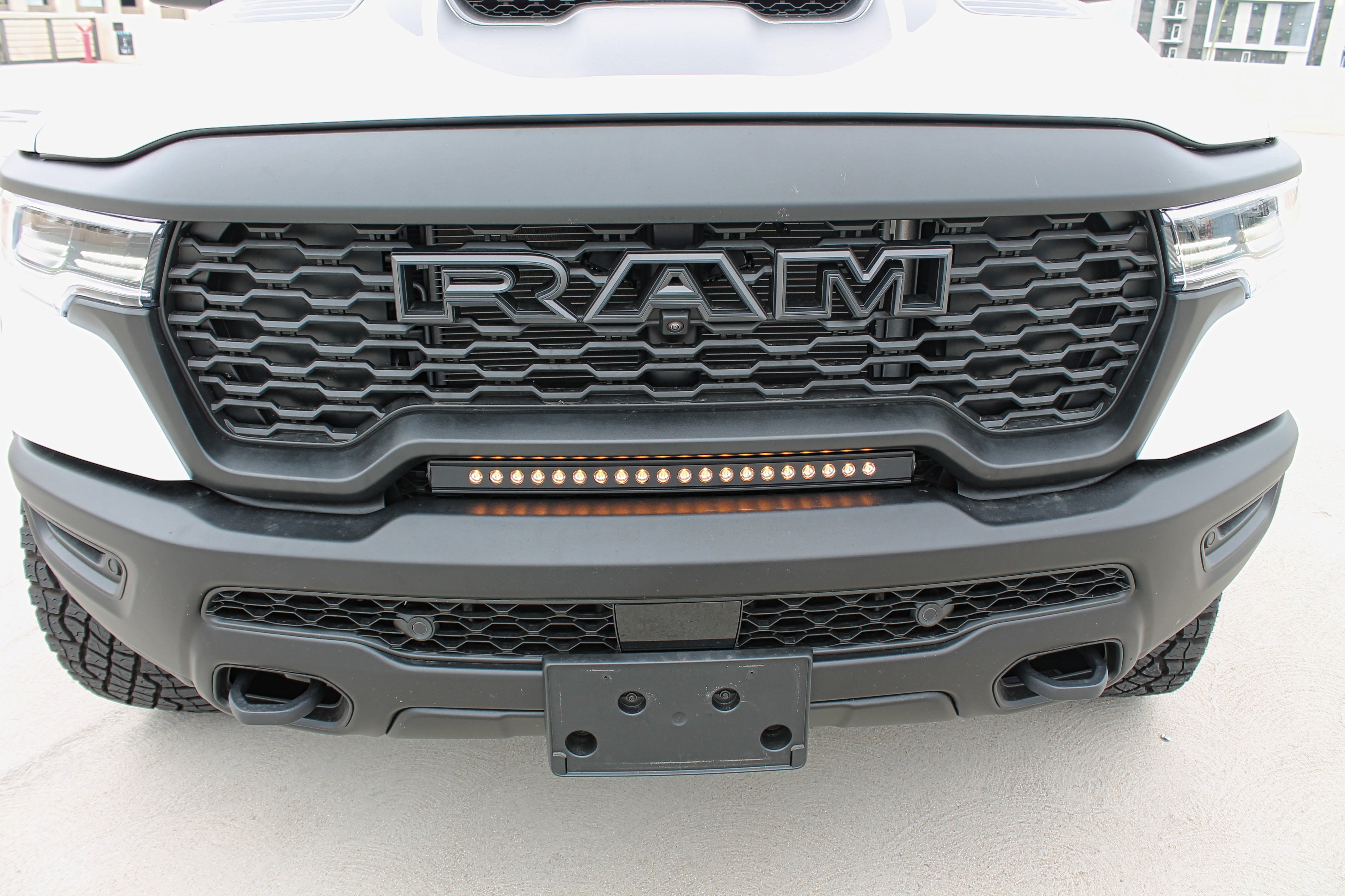 RAM RHO lightbar on 2025+ RAM 1500 Rebel with slim curved installation between grille and bumper, metal black powder-coated bracket, built-in sleek look