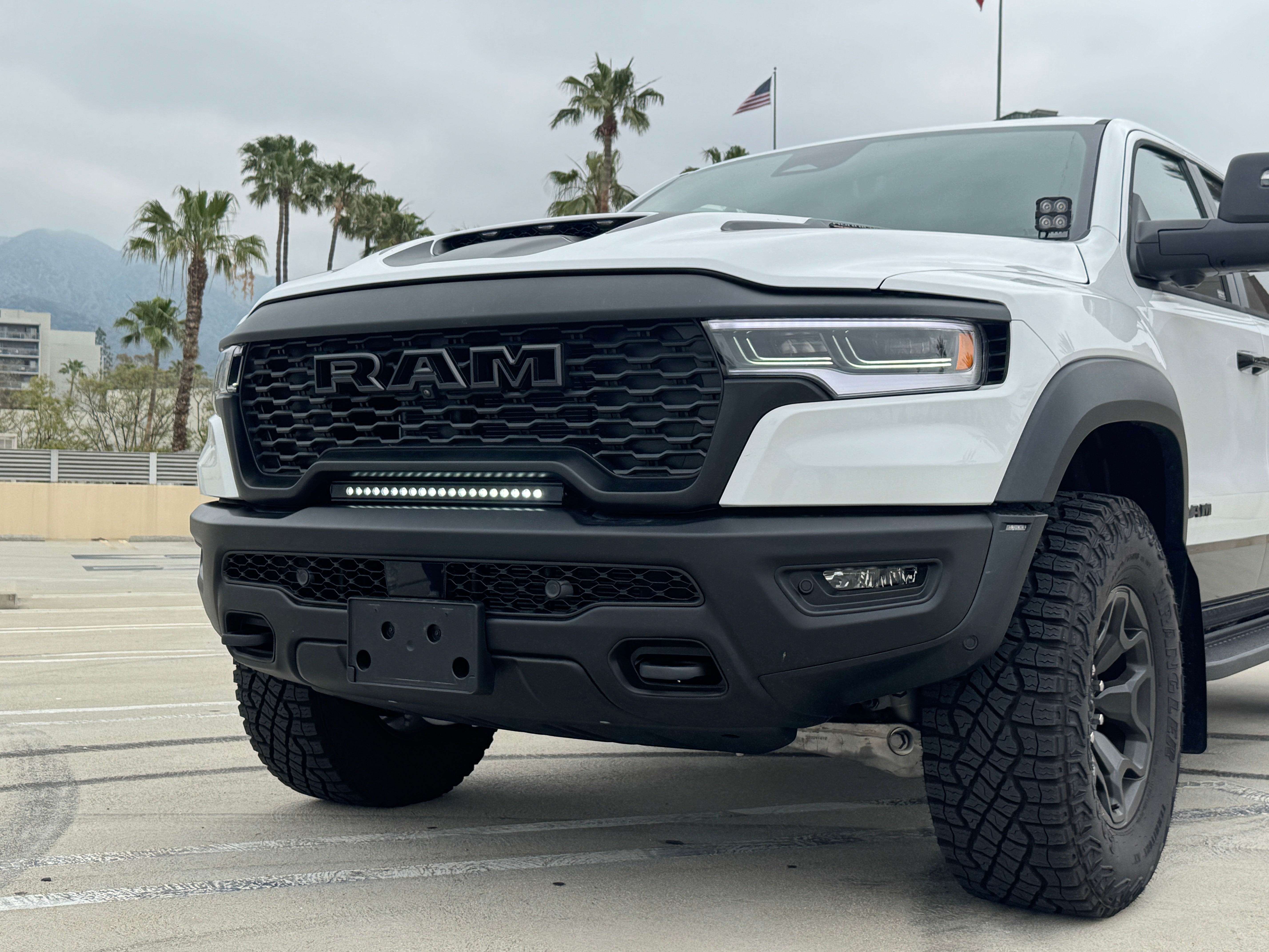 RAM RHO lightbar fits 2025 2026 RAM 1500 Rebel with slim curved profile between grille and bumper; RAM RHO lightbar for 23in slim height, powder coated black bracket