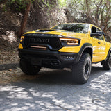 RAM TRX Light bar slim 23in installed in grille opening on yellow 2021-2024 RAM 1500 TRX driving on shaded road