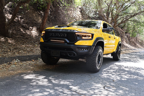 RAM TRX Light bar slim 23in installed in grille opening on yellow 2021-2024 RAM 1500 TRX driving on shaded road