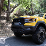 RAM TRX Light bar slim 23in installed on yellow 2021-2024 RAM 1500 TRX between grille and bumper on forest road