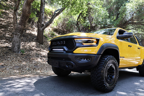 RAM TRX Light bar slim 23in installed on yellow 2021-2024 RAM 1500 TRX between grille and bumper on forest road