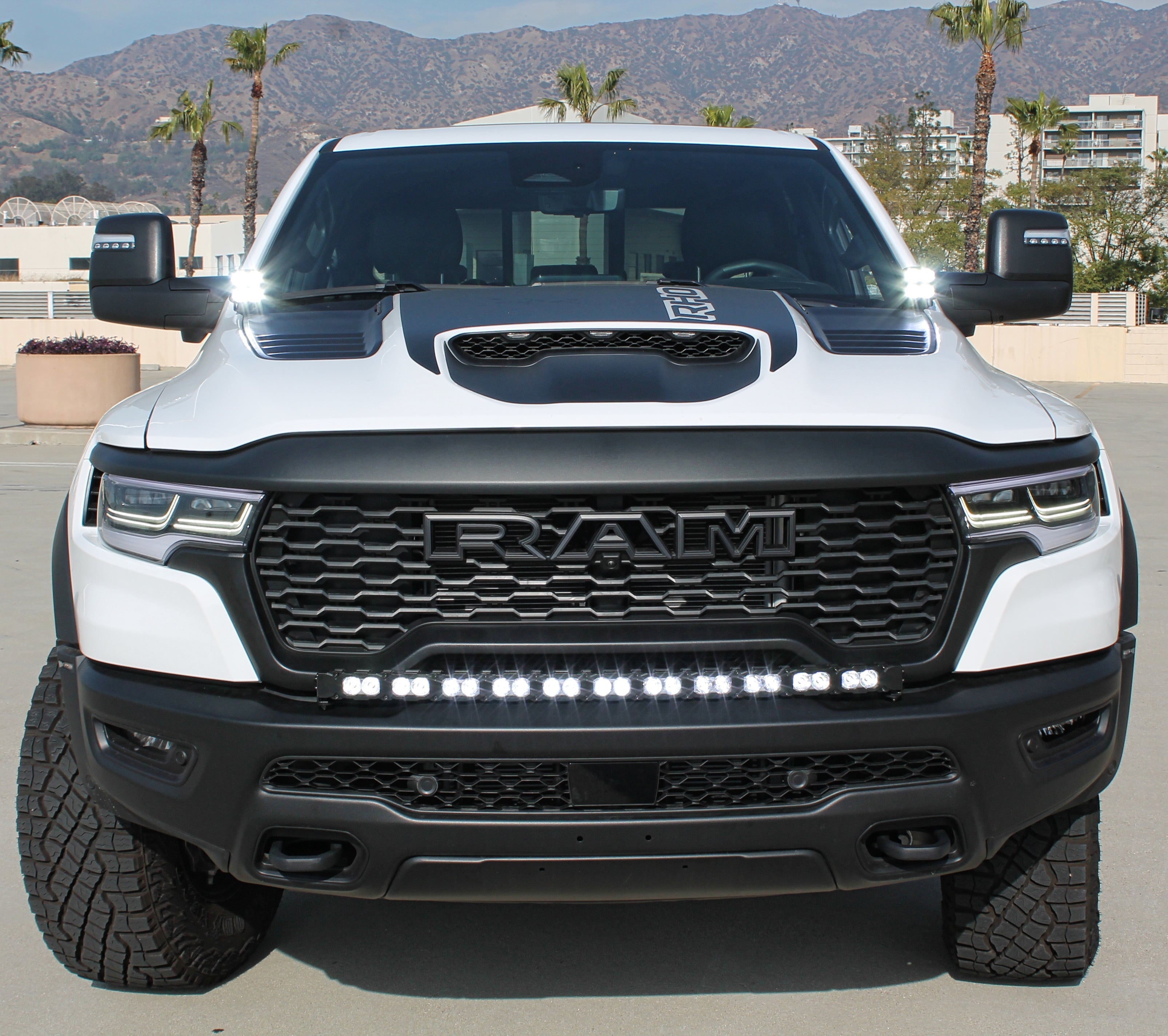 RAM RHO Ditch Lights - PRO 2025+ on RAM 1500 with dual white LED and amber DRL backglow under hood, rugged front view