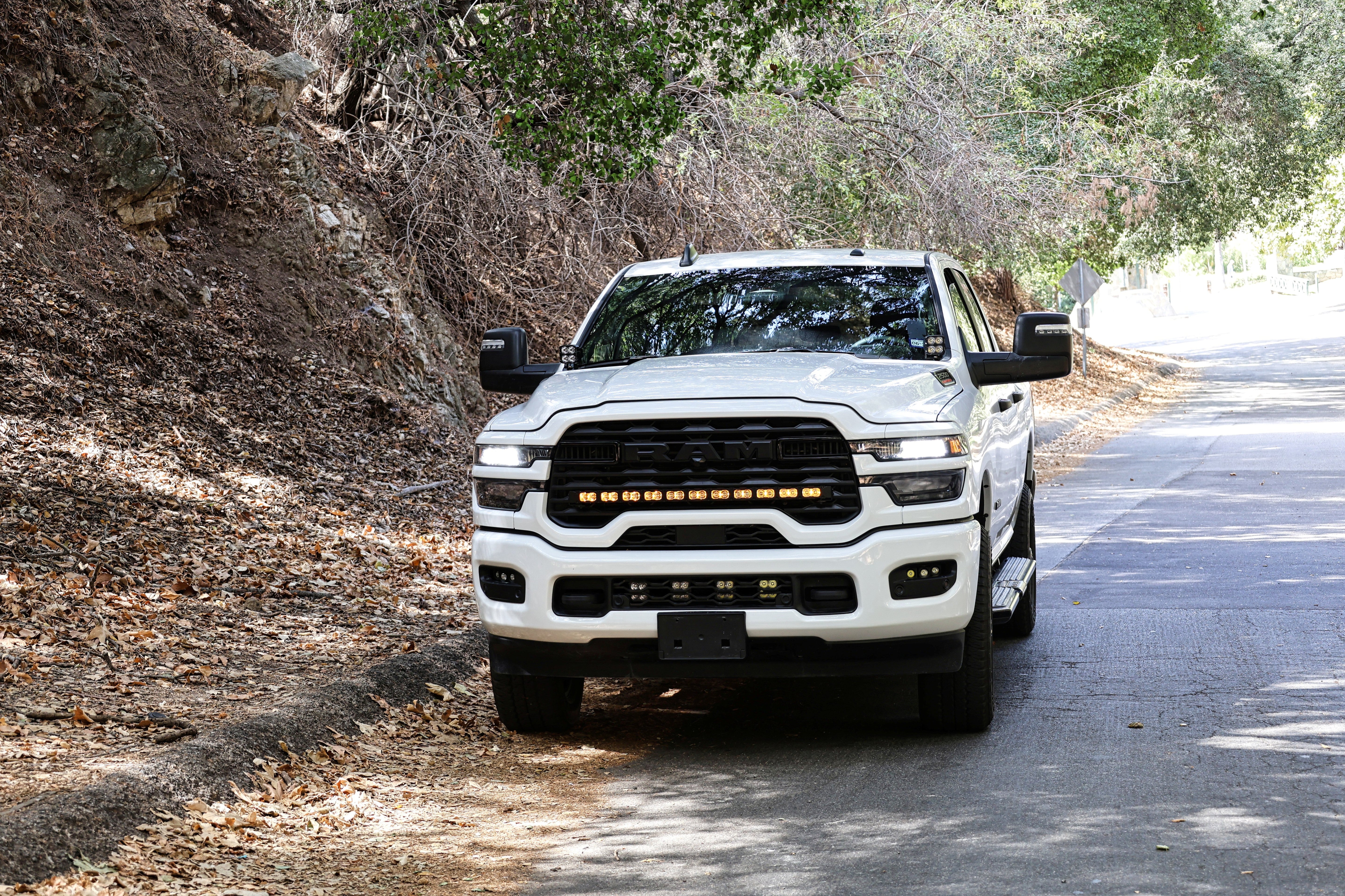 2025+ RAM 2500 Light kit lower grille pods installed on white RAM 2500 truck driving on wooded road