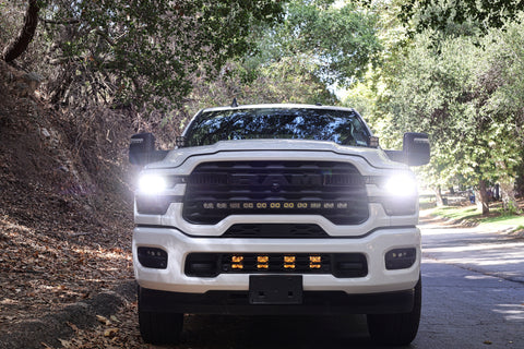 2025+ RAM 2500 Light kit lower grille pods with bright LED lights installed on white RAM 2500 truck front view on forest road
