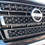 black nissan titan with off road led light bars behind the grille up close view