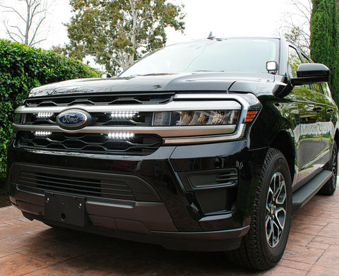black ford expedition with white ditch lights and white led light bar behind the grille for off roading