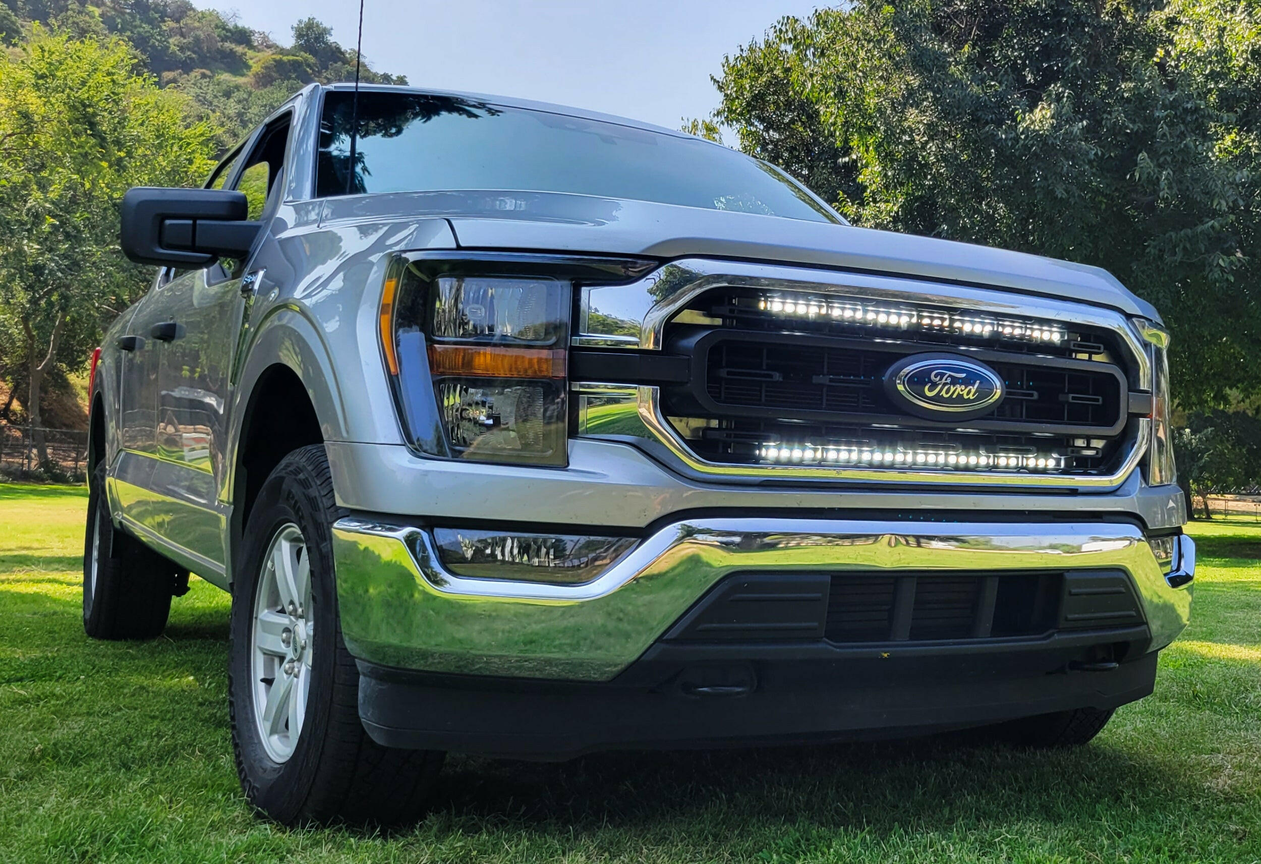 gray 2021 2022 2023 ford f150 with 2 white 30in light bars behind the grille 