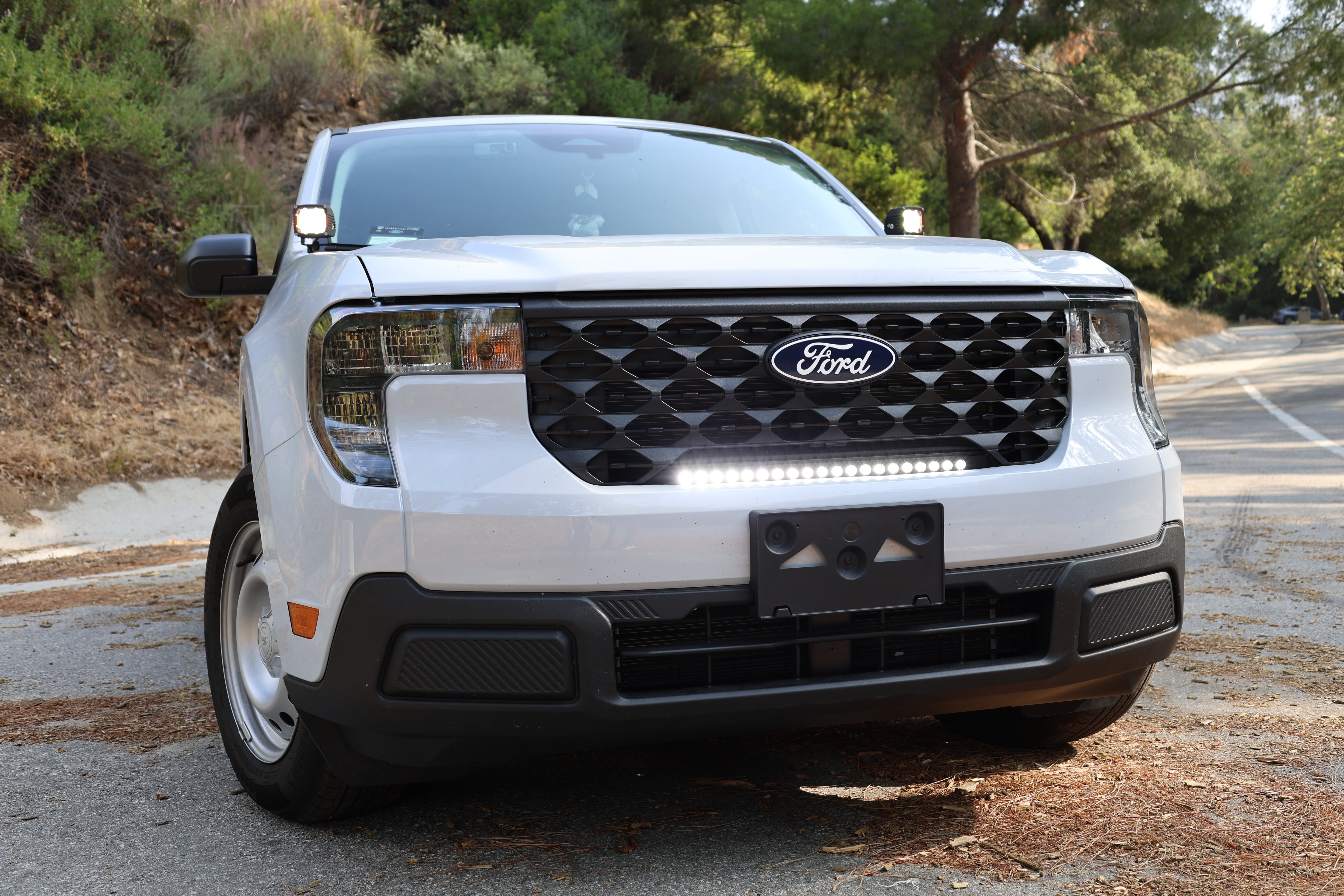 ford maverick light bar 23in curved slim grille mount on white 2025 Ford Maverick XL truck front view on forest road