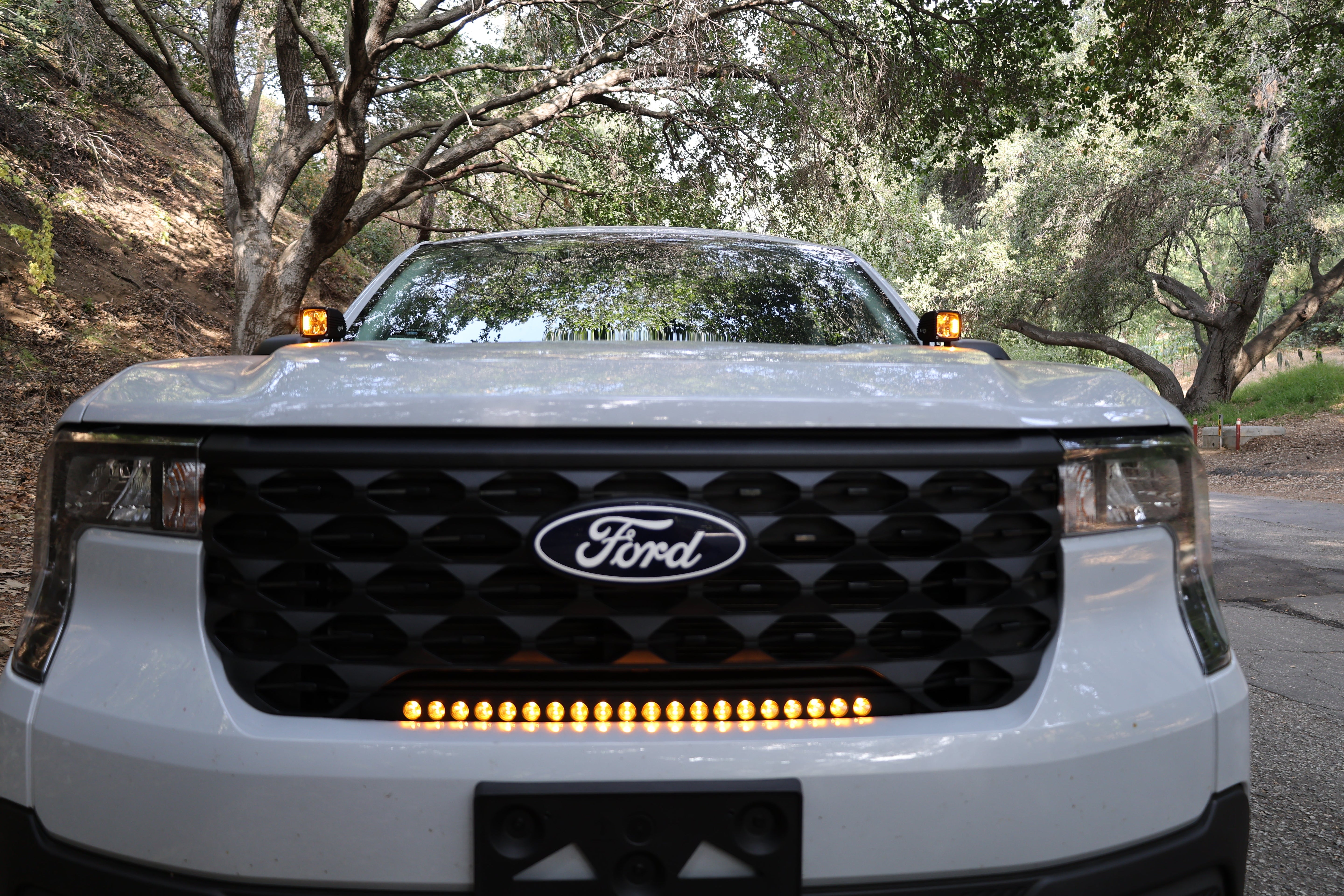 ford maverick light bar 23in installed on 2025 Ford Maverick grille, slim curved amber LED light bar glowing on front bumper