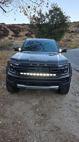 Ranger Raptor ditch lights dual color LED bar on front of 2024+ Ford Ranger Raptor in rugged off-road setting