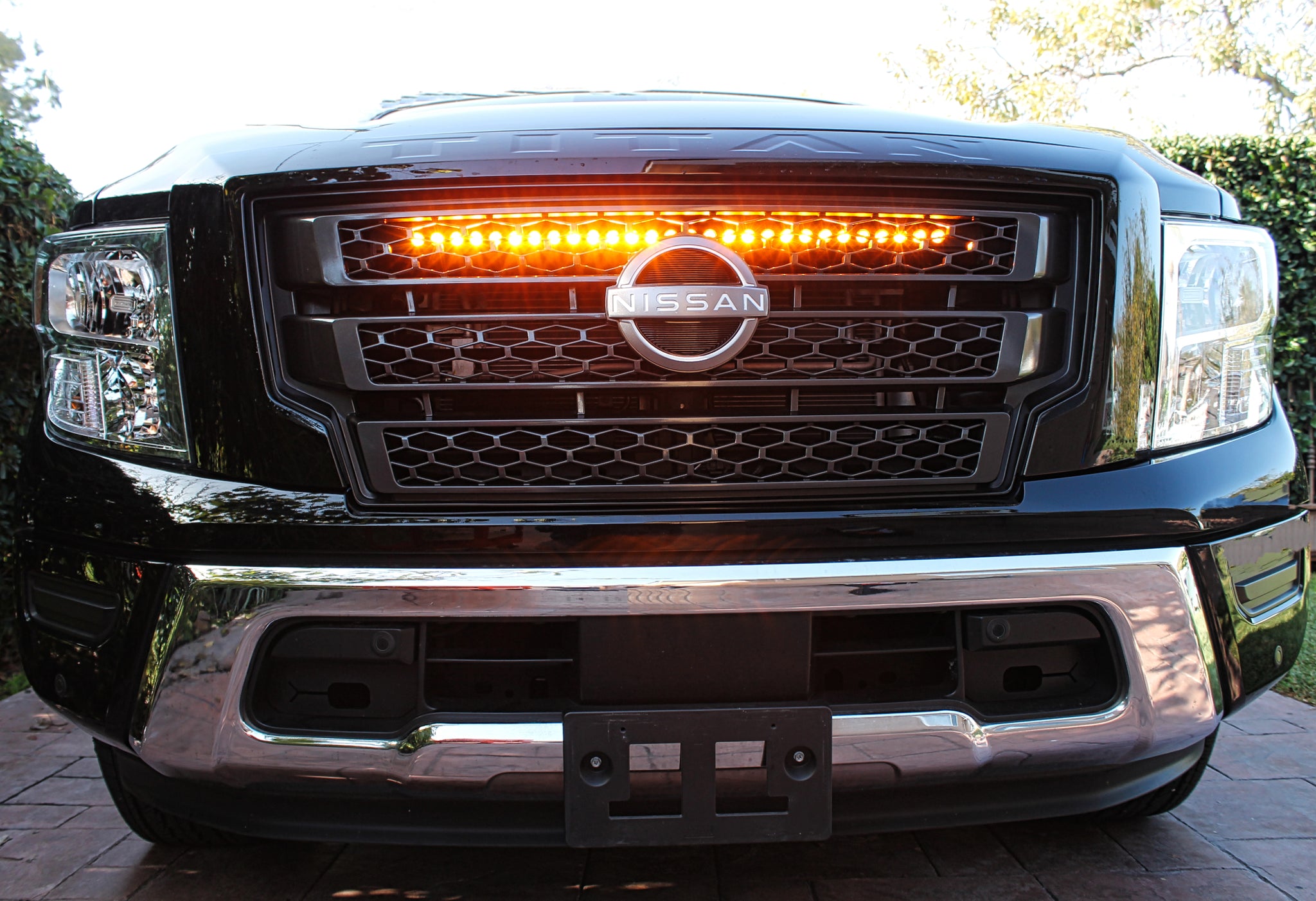 black nissan titan with one led light bar behind the grille in amber color for off roading