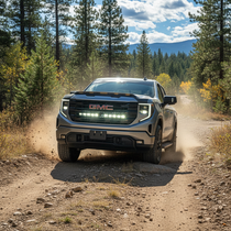2019-2026 GMC Sierra 1500 Light Bar PRO installed in grille, white off-road LED light bar kicking up dust on forest trail