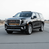 GMC Yukon with a single 40in light bar mounted under the logo on a clear road.