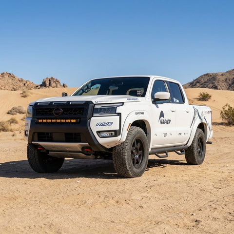 2025+ Nissan Frontier in desert with ditch lights, showcasing vibrant design and outdoor adventure capability.