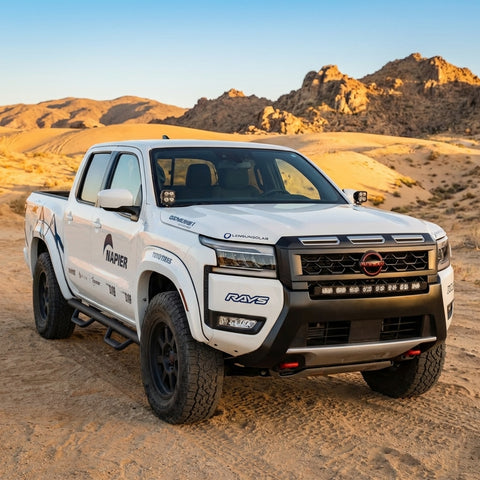 2025+ Nissan Frontier with ditch lights in desert landscape, showcasing a striking white truck design.