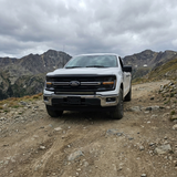 2024+ Ford F150 LightBar installed on a white Ford F150 driving on a rugged off-road trail.