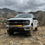 2024+ Ford F150 LightBar mounted on a white Ford F150 in a rugged mountain landscape.