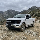 2024+ Ford F150 LightBar installed on a white Ford F150 pickup in rugged terrain.