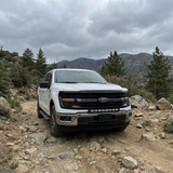 2024+ Ford F150 LightBar mounted on a white truck in a rugged outdoor setting with trees and mountains.