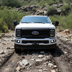 Front view of a 2023 Ford Super Duty F250 with fog lights on a rugged terrain, showcasing Ford Super Duty Fog Lights.