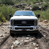 Front view of a 2023 Ford Super Duty F250 with fog lights on a rugged terrain, showcasing Ford Super Duty Fog Lights.