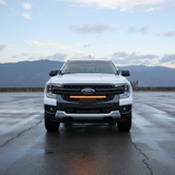 Front of a white Ford Ranger fitted with the 30-inch SLIM LED grille light bar, mountains behind