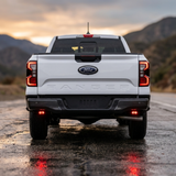 Rear of a white Ford Ranger with the reverse light kit pods showing red backlight