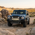 Blue 2024+ Ineos Grenadier parked among desert boulders at sunset with 30in bumper light bar, off-road setup