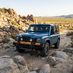 Blue 2024+ Ineos Grenadier on desert rocks with XL light bar kit (30in center plus two 12in extensions) lit amber