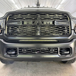 Straight-on front view of a gray 2019-2024 RAM 2500 in a shop with the 30in light bar running amber below the grille