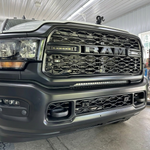 Close-up of the 30in light bar mounted in the lower grille of a gray 2019-2024 RAM 2500, lights off, showing the black bracket and bumper fitment