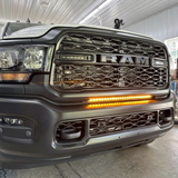 Close-up of the 30in light bar lit amber in the lower grille of a gray 2019-2024 RAM 2500 in a shop