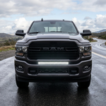 Gray 2019-2024 RAM 2500 straight-on front view on a wet road with the 30in light bar lit white in the lower grille