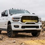 2025+ RAM 2500 40in PRO grille light bar lit in yellow on a white truck in the desert, front corner view