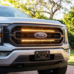 Close-up of a 2021-2023 Ford F150 grille with dual amber 30in LED light bars lit above and below the Ford emblem