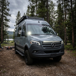 Front three-quarter view of a 2019+ Mercedes Sprinter van at camp with a 40in SLIM light bar lit white on the grille
