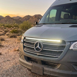 Close-up of a 2019+ Mercedes Sprinter grille with a 40in SLIM LED light bar lit white at sunset, mounted under the hood line