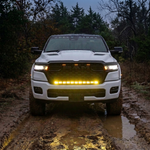 2026 RAM 1500 HEMI head-on with 40in light bar PRO glowing yellow on a muddy trail at dusk