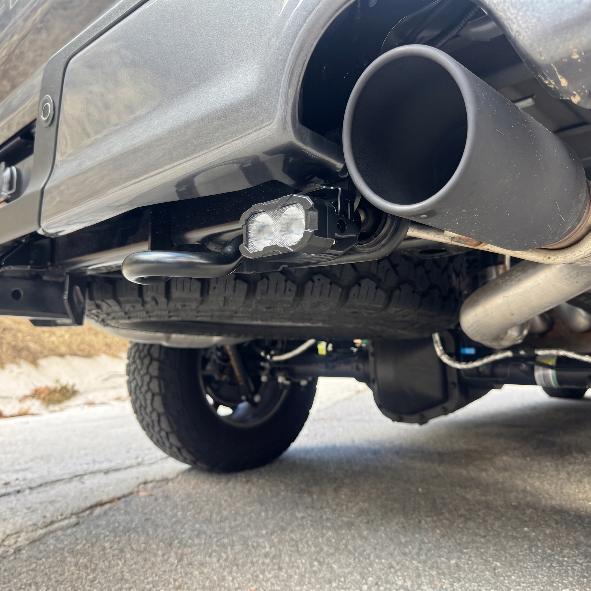 2023 Ford F-150 Tremor reverse light pod and bracket mounted under the rear bumper next to the exhaust, lights off