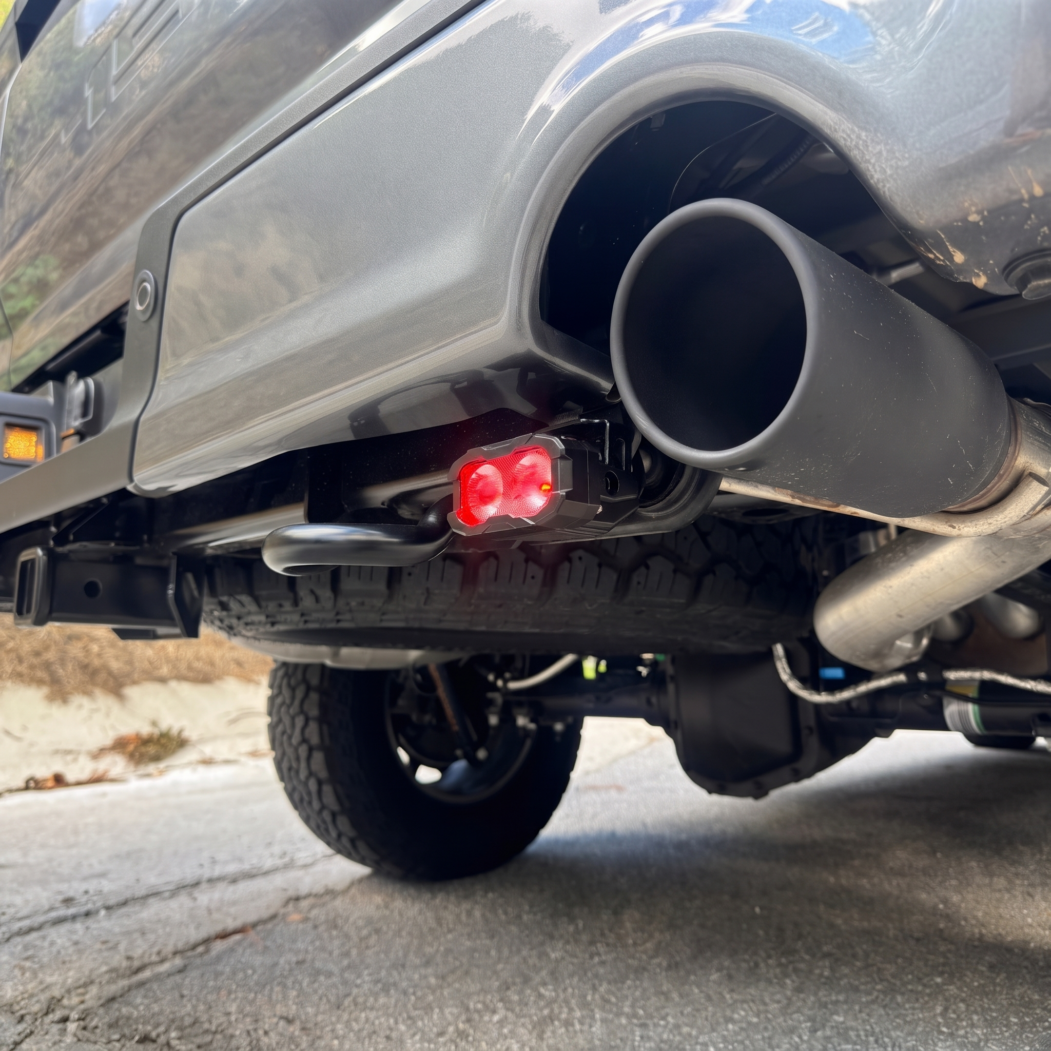 2025 Ford F-150 Tremor reverse light close-up with red backlight on, mounted under the rear bumper