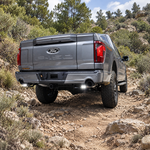 2021 Ford F-150 Tremor on an off-road trail with M&R reverse light kit, white off-road light on both rear pods, rear three-quarter view