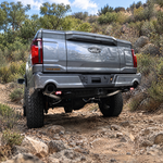 2023 Ford F-150 Tremor reverse light kit with red backlight glowing on both pods, low rear three-quarter view on an off-road trail