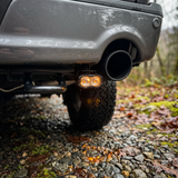 2022 Ford F-150 reverse light close-up, 20W PRO pod with amber backlight glowing on the gravel under the bumper