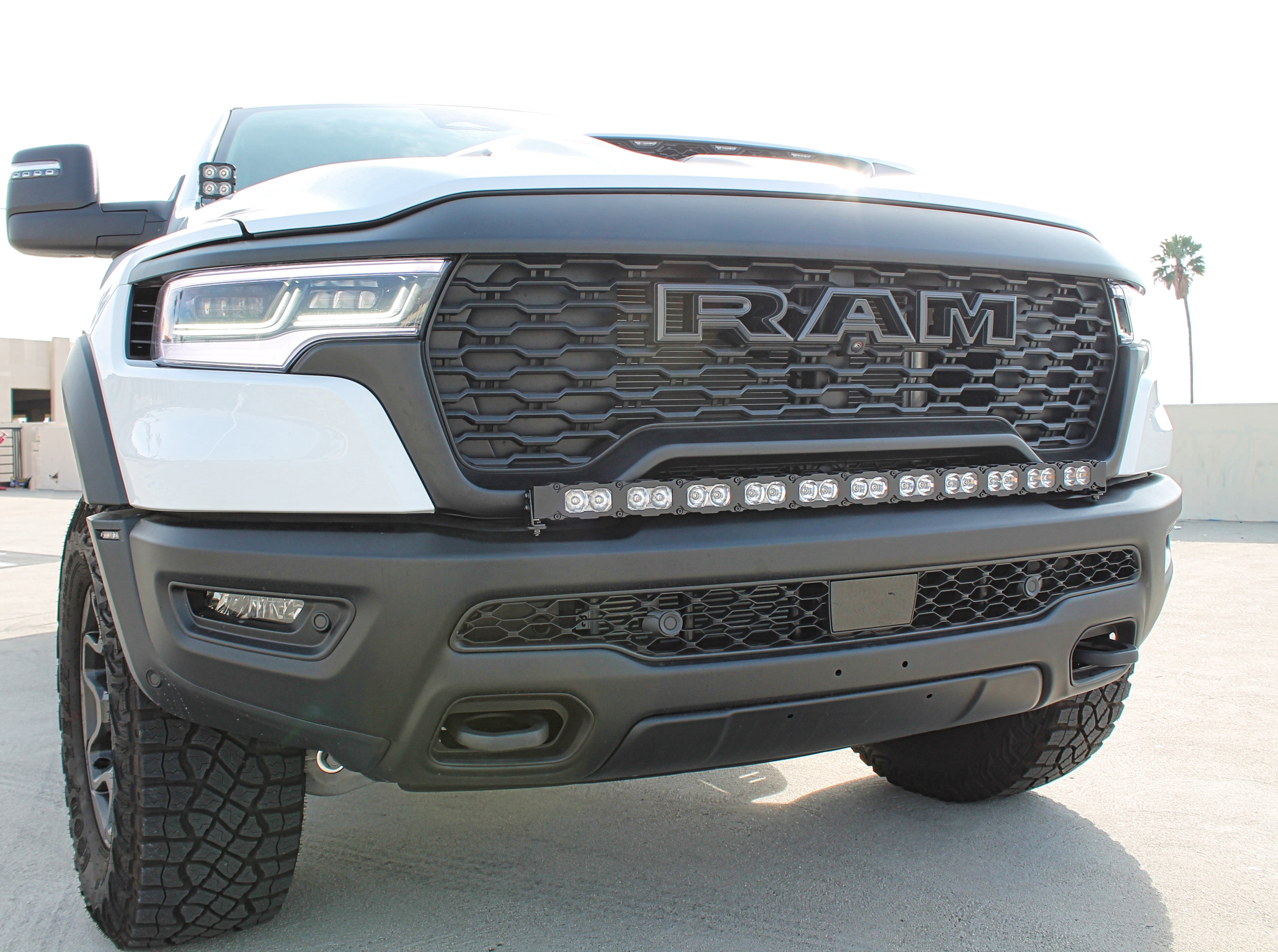 RAM RHO Ditch Lights on RAM 1500 PRO 2025+ front view with dual-color white LED and amber DRL backglow