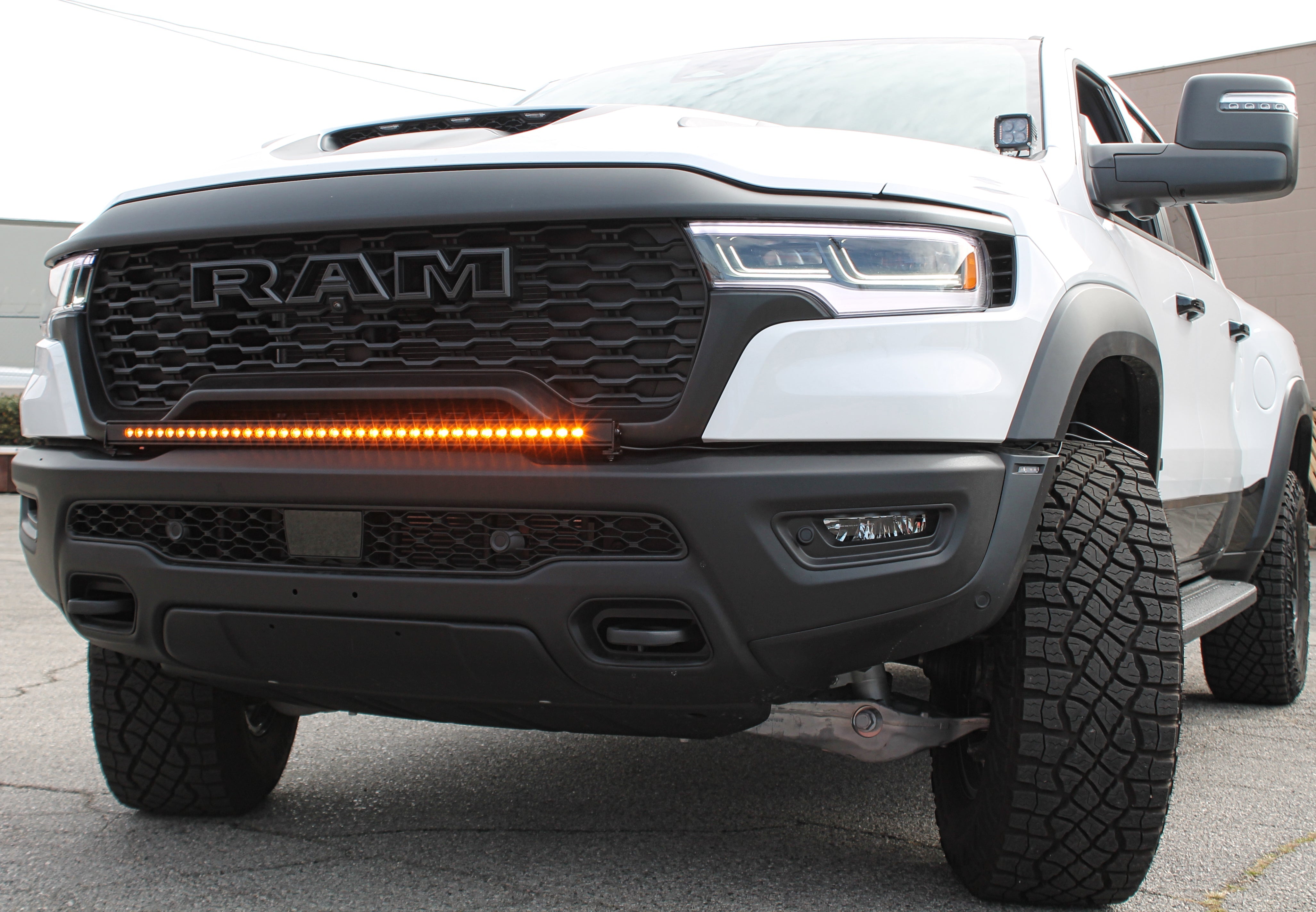 RAM RHO Lightbar on 2025+ RAM 1500 RHO, curved slim light bar following bumper curvature with black powder-coated bracket, no grille cut needed