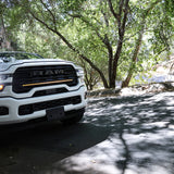 2025+ RAM 2500 light bar slim 40in curved LED grille mount on white RAM truck driving through shaded forest road
