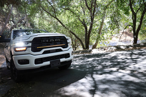 2025+ RAM 2500 light bar slim 40in curved LED grille mount on white RAM truck driving through shaded forest road